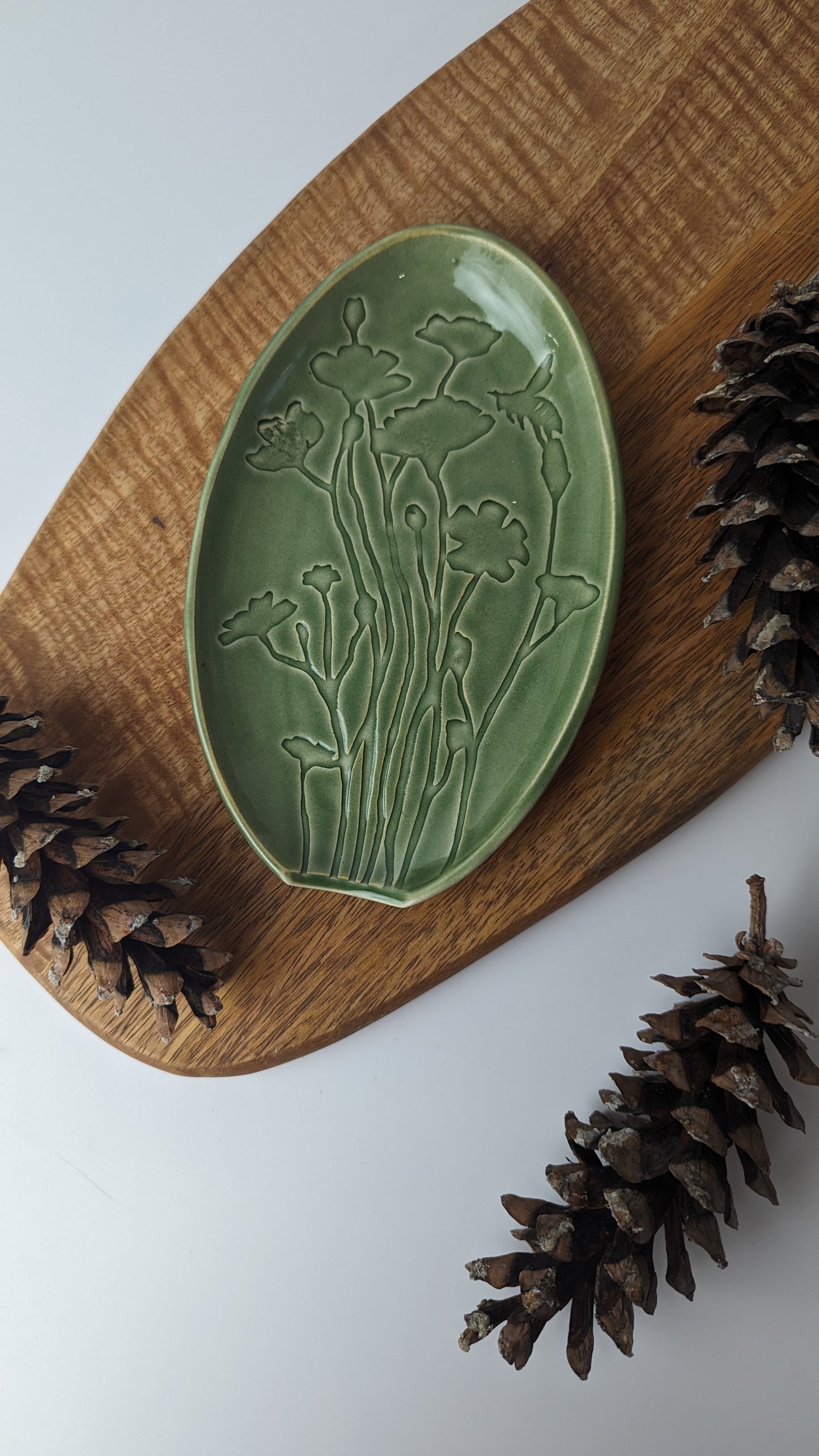 Close-up of a green Spoon Rest adorned with Poppy Flowers and Bees, highlighting its handmade artistry.