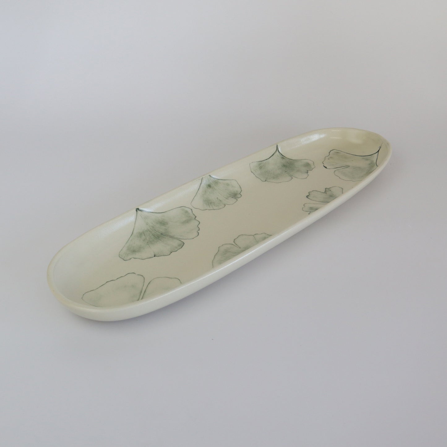 Close-up of a handmade porcelain service plate with a Ginkgo leaf pattern, highlighting its unique details and quality.