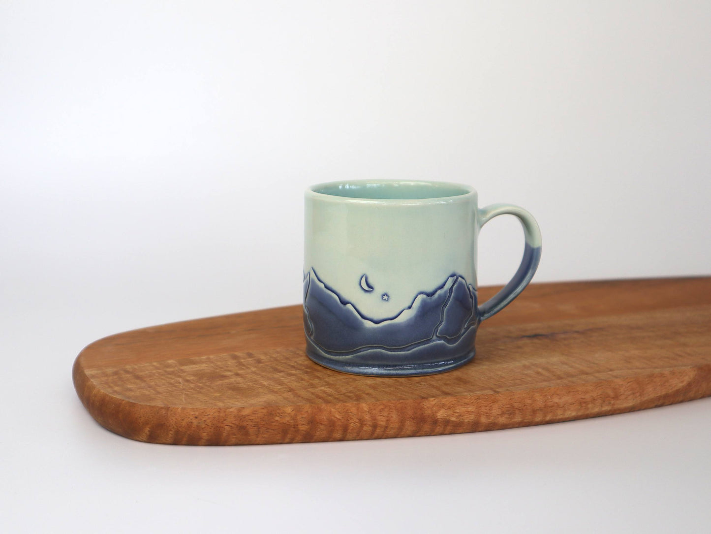 Handmade Mountain Range Mug showcasing a crescent moon and mountain design against a light background.